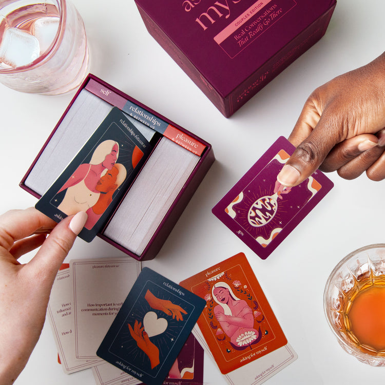 Hands reaching for and pulling questions from the Asking for Myself Couples Edition card deck